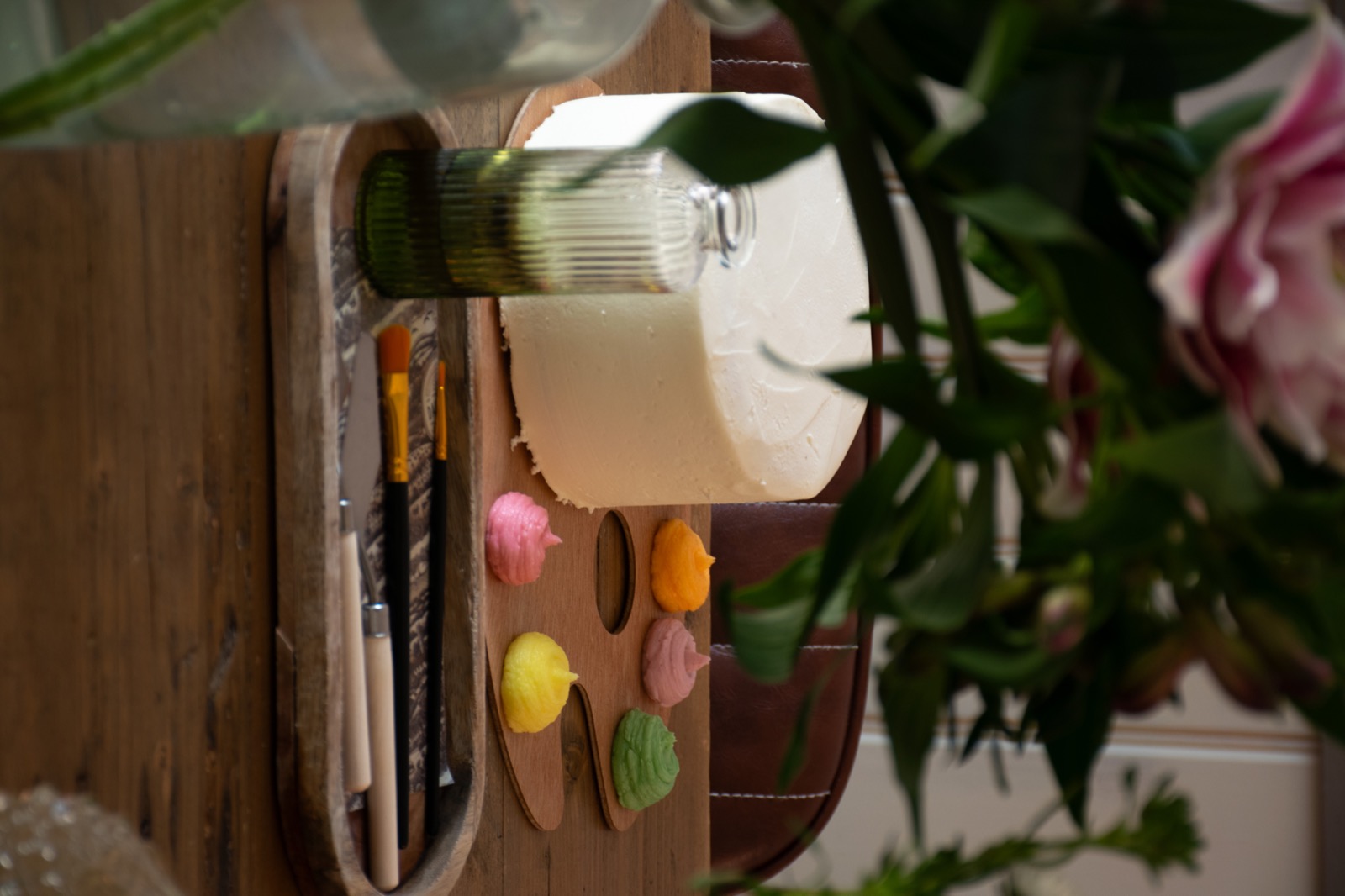 An iced cake, colourful icing and brushes ready on the table