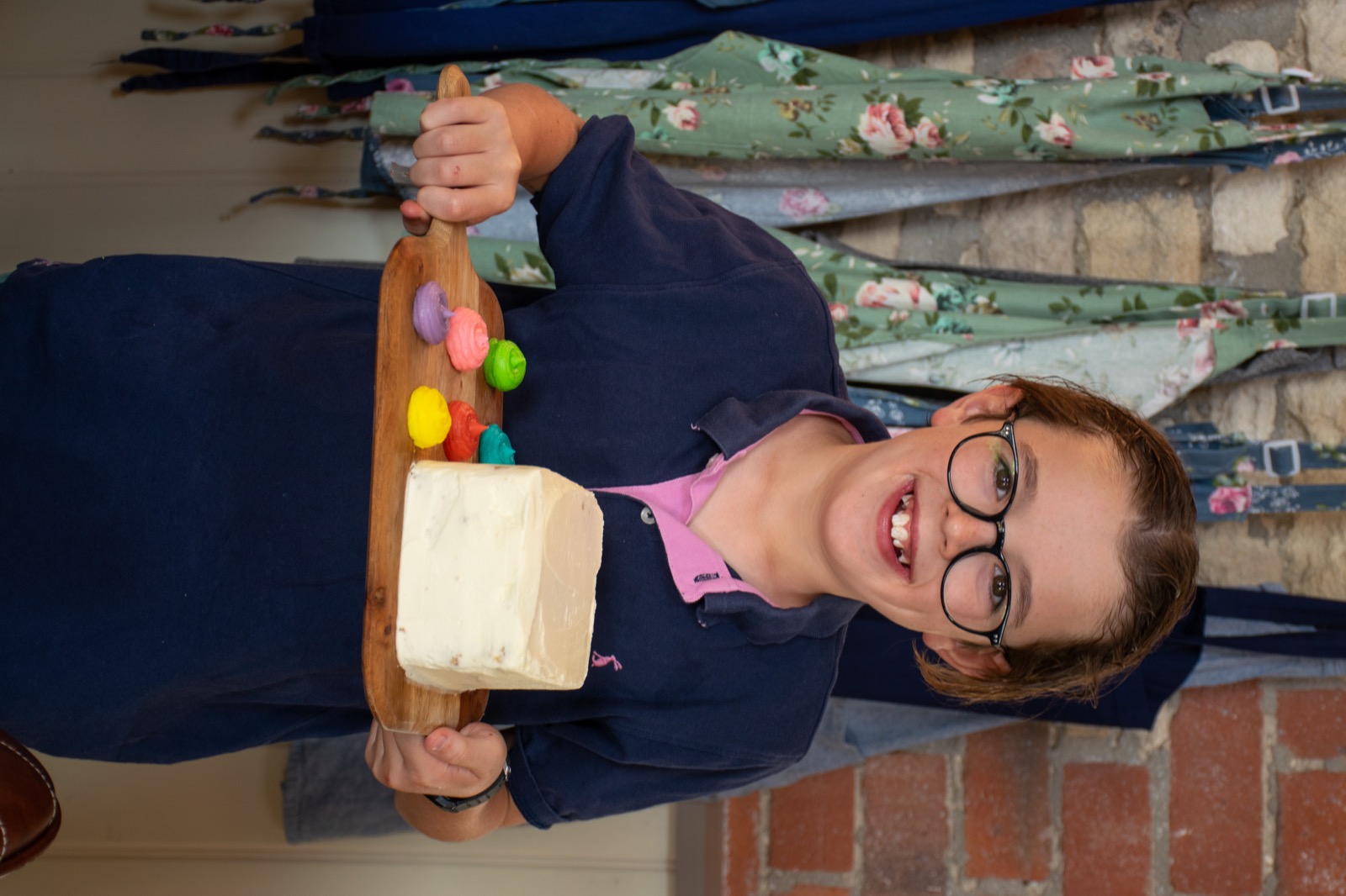 A young guest holding a cake and a palette of colourful icing