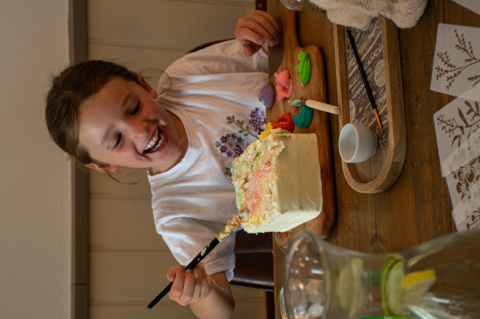 A smiling young guest using a brush to paint her cake at the workshop table