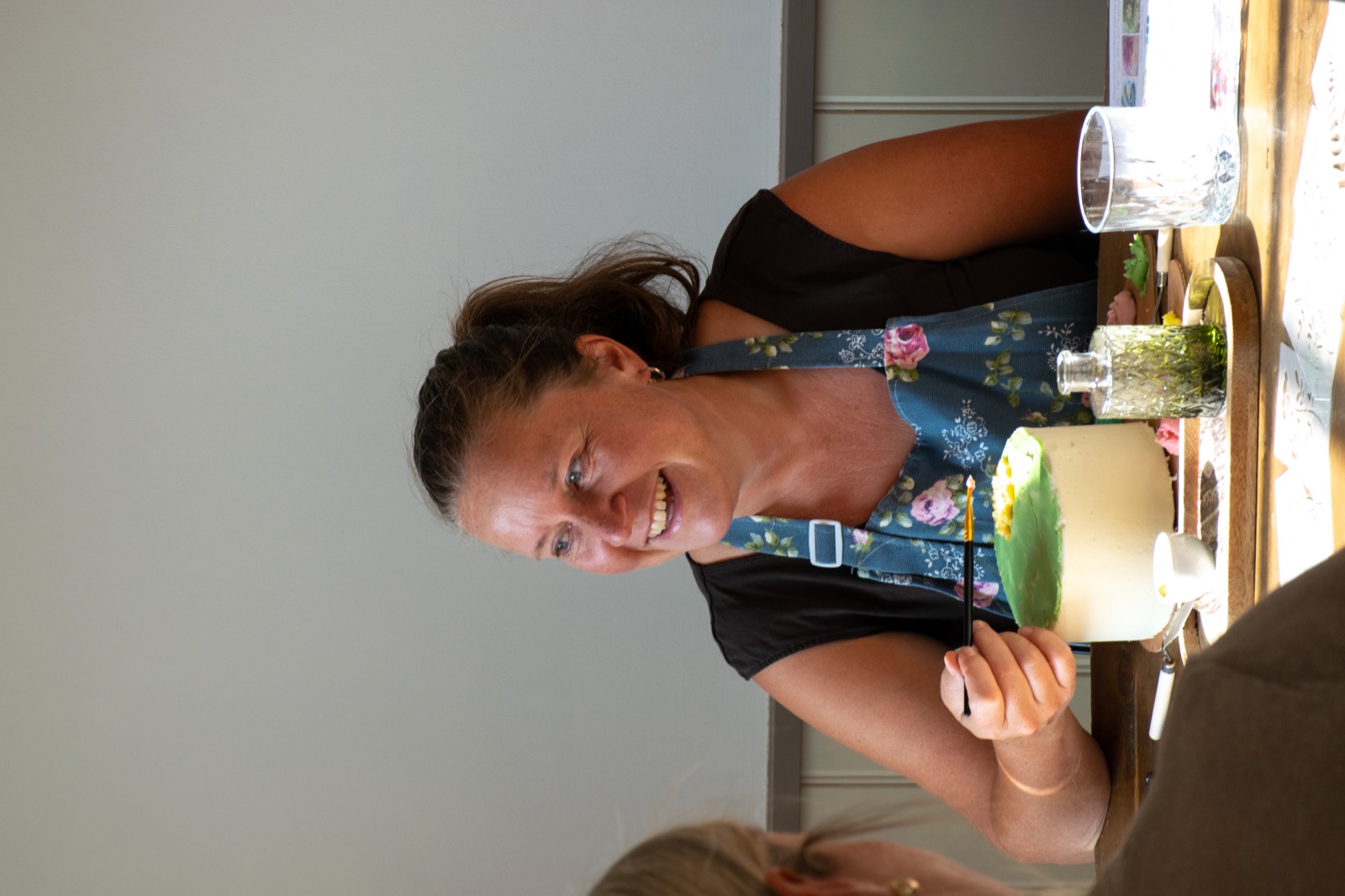 A smiling guest painting her cake at the table