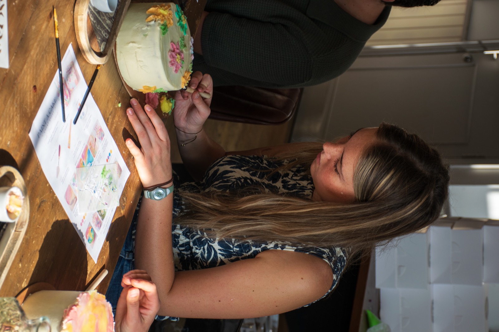 A guest adding careful brushstrokes to her cake