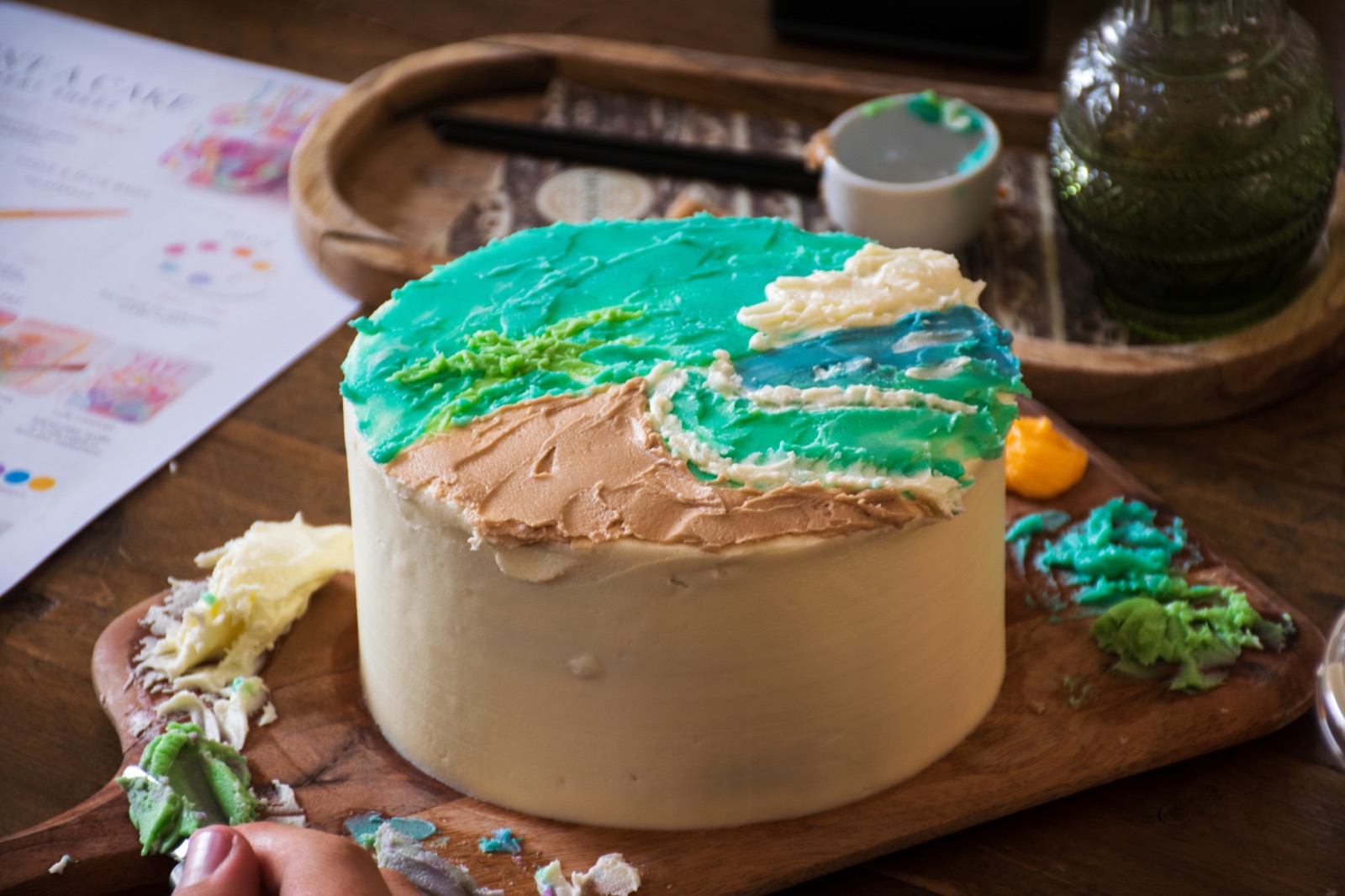 A finished cake painted with a blue landscape scene