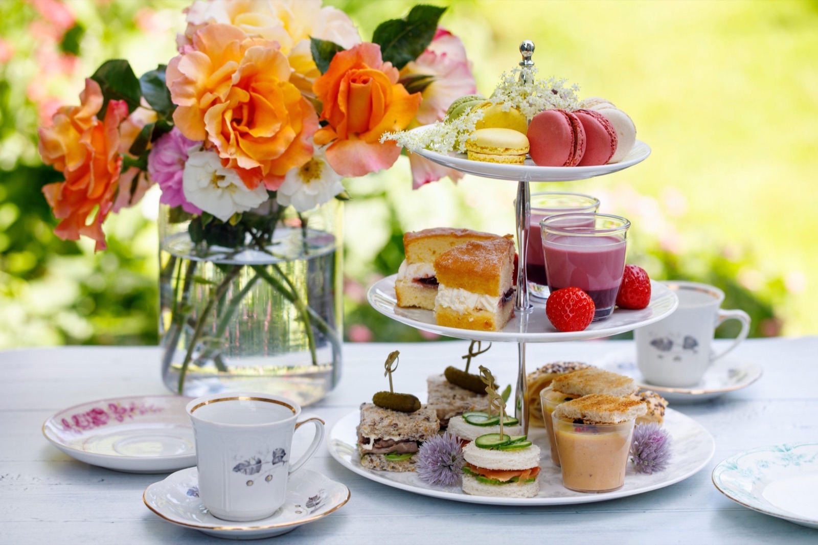 An afternoon tea stand with cakes, sandwiches and colourful macarons